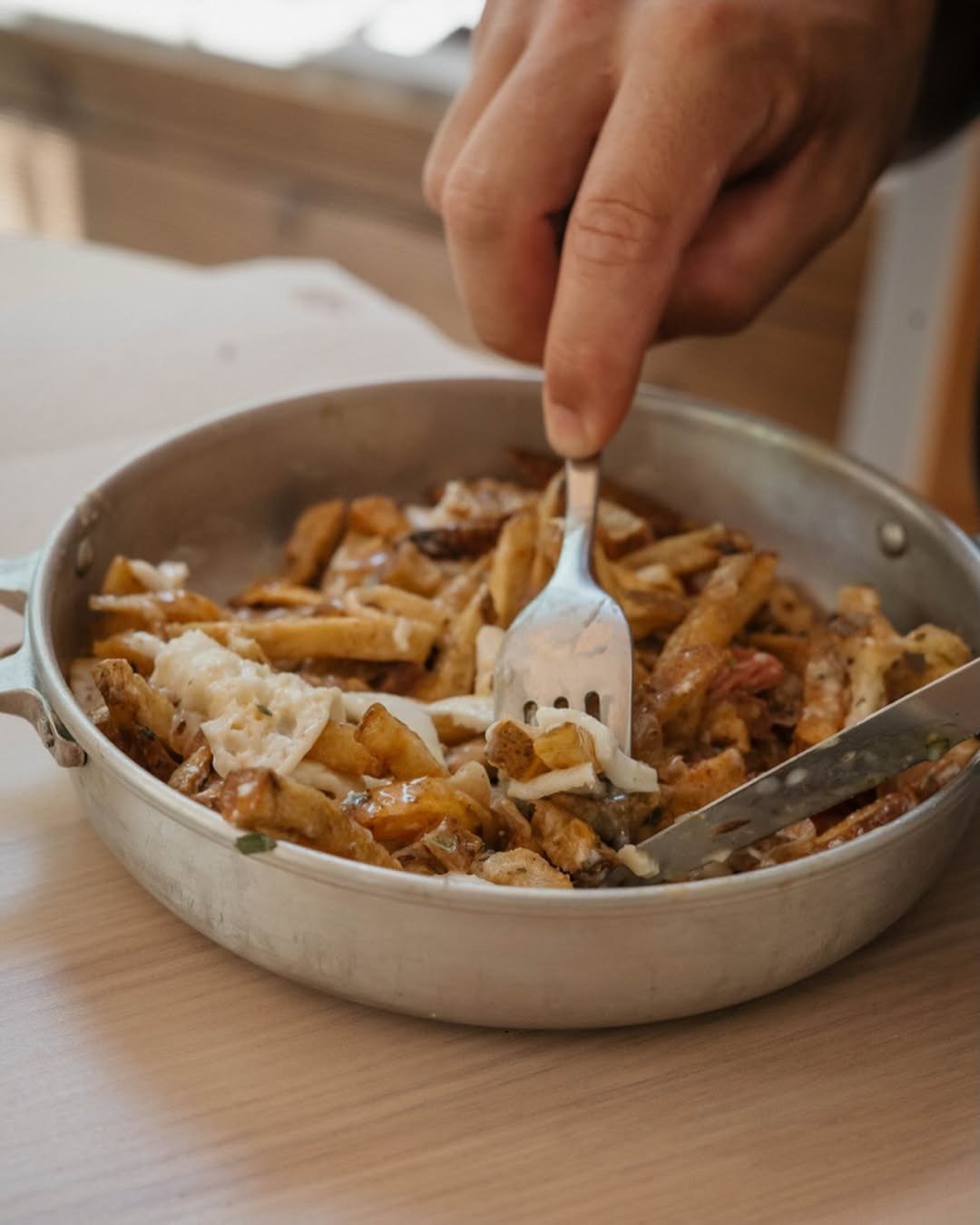 Frigideira de metal com batatas fritas e ovo, a ser servida com um garfo